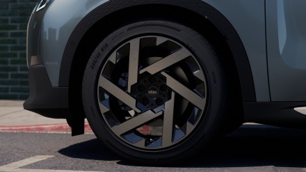 Nahaufnahme eines MINI-Autoreifens mit futuristischem Felgendesign auf Asphalt.