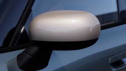 Nahaufnahme eines beigen Seitenspiegels eines Autos vor blauem Hintergrund.