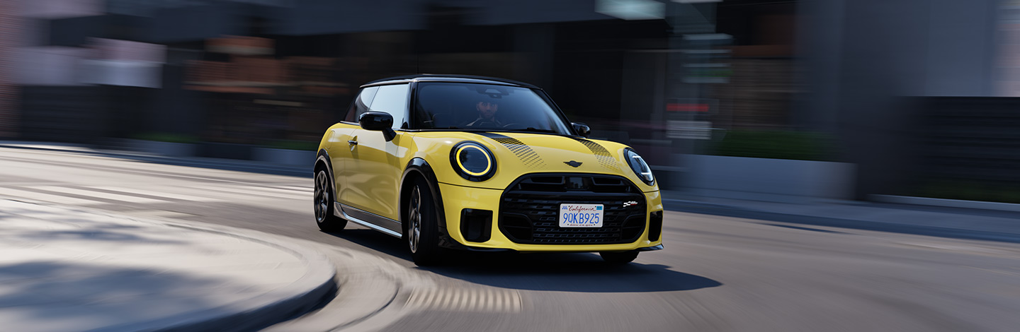 Gelber MINI Cooper fährt auf städtischer Straße, Gebäude im Hintergrund.